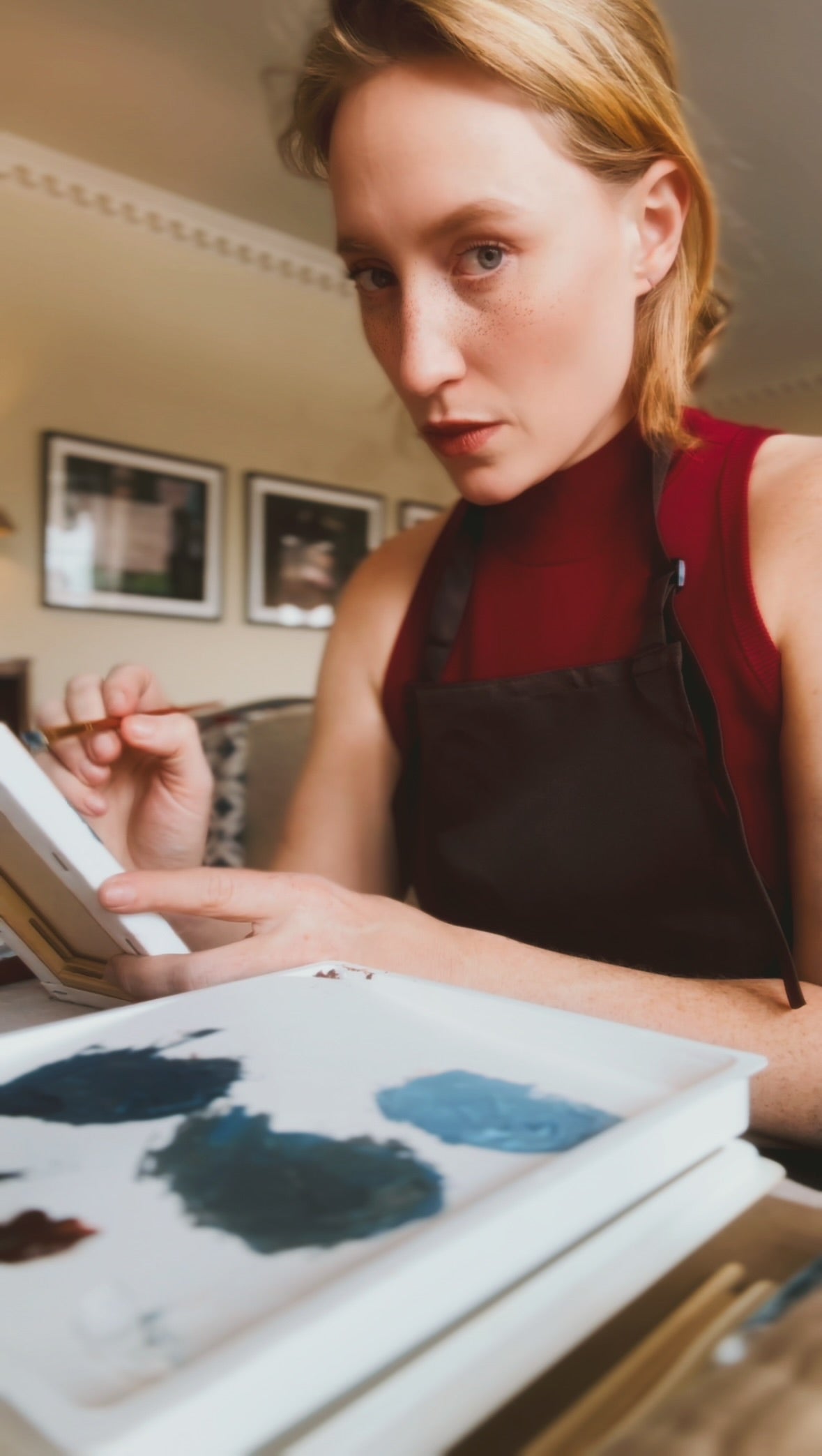 Woman painting with a brush and color swatches in a studio setting